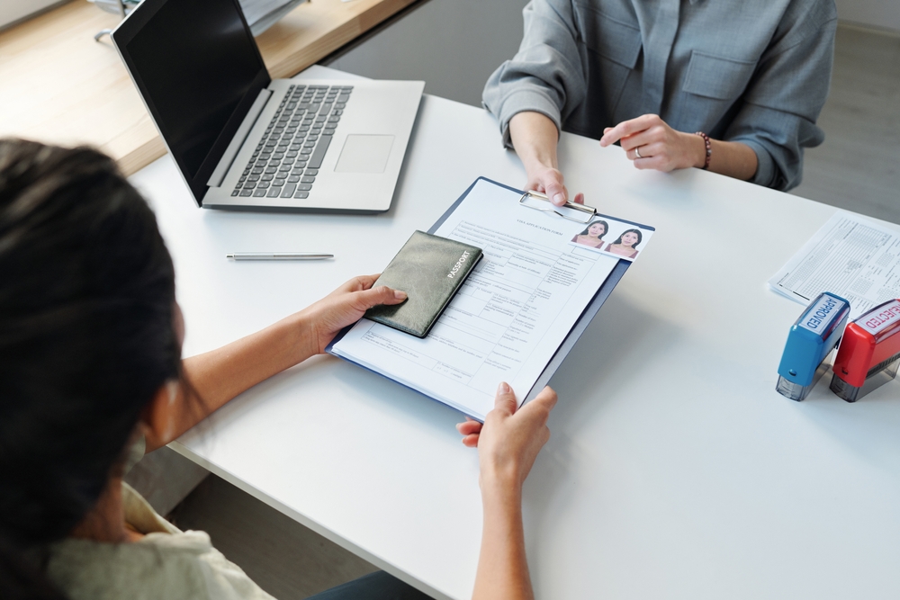 Woman,Applying,For,Visa,At,Table A woman submitting a residency application form