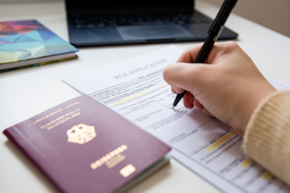 Close,Up,Of,Female,Hand,Filling,Out,A,Visa,Application A woman applying for a Golden Visa programme
