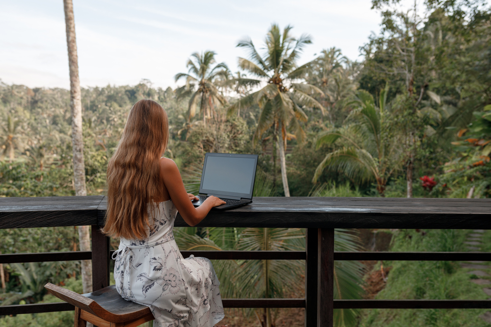 A woman talks on the phone while working outdoors, a benefit of having a digital nomad visa.