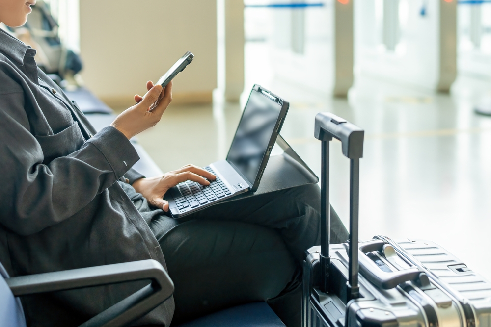 A woman works on her laptop at an airport, representing a perk of having a digital nomad visa.
